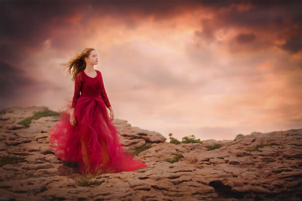 image-of-a-girl-in-a-red-dress-standing-on-the-rocks-of-a-mountain-at-Mallorca-beach-by-Willie-Kers